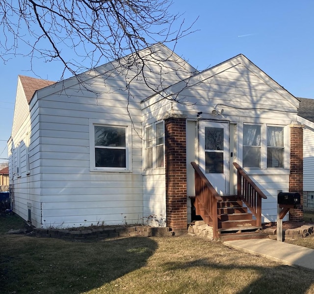 view of front of home with entry steps and a front lawn