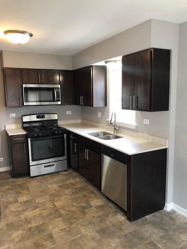 kitchen featuring dark brown cabinetry, sink, stainless steel appliances, and tile patterned floors