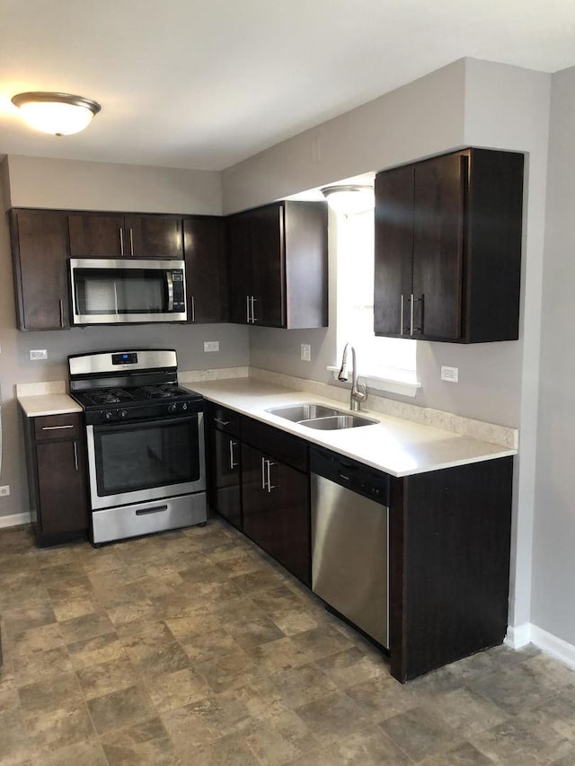 kitchen featuring appliances with stainless steel finishes, dark brown cabinets, and sink