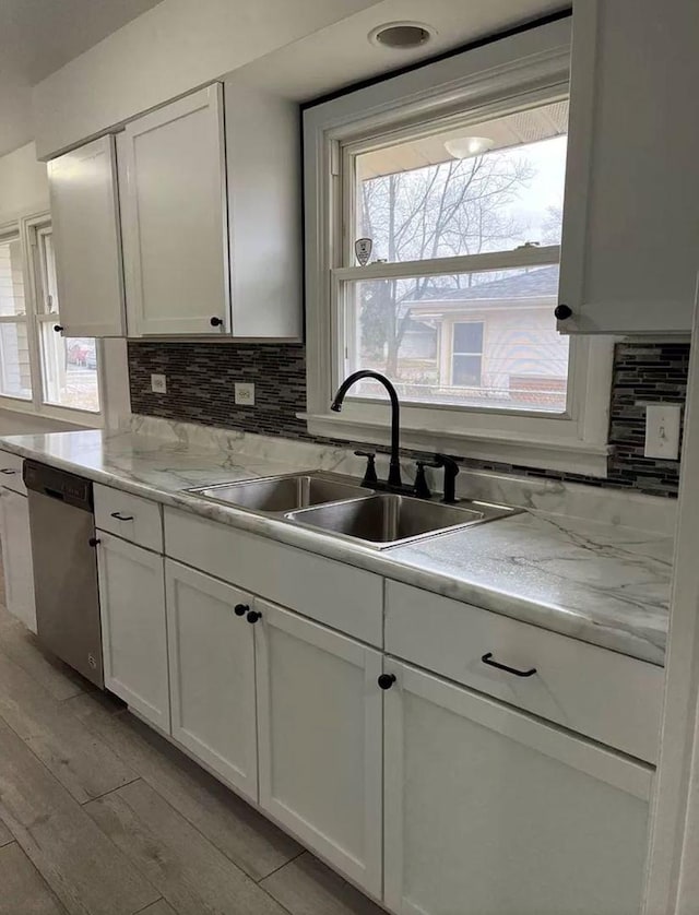 kitchen featuring white cabinetry, dishwasher, sink, and light stone counters