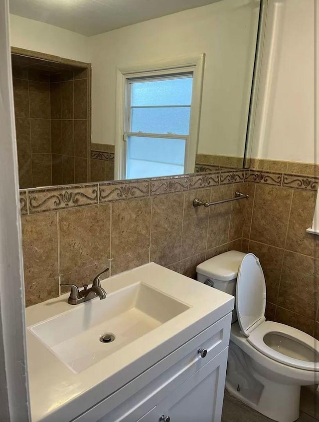 bathroom with vanity, tile walls, and toilet