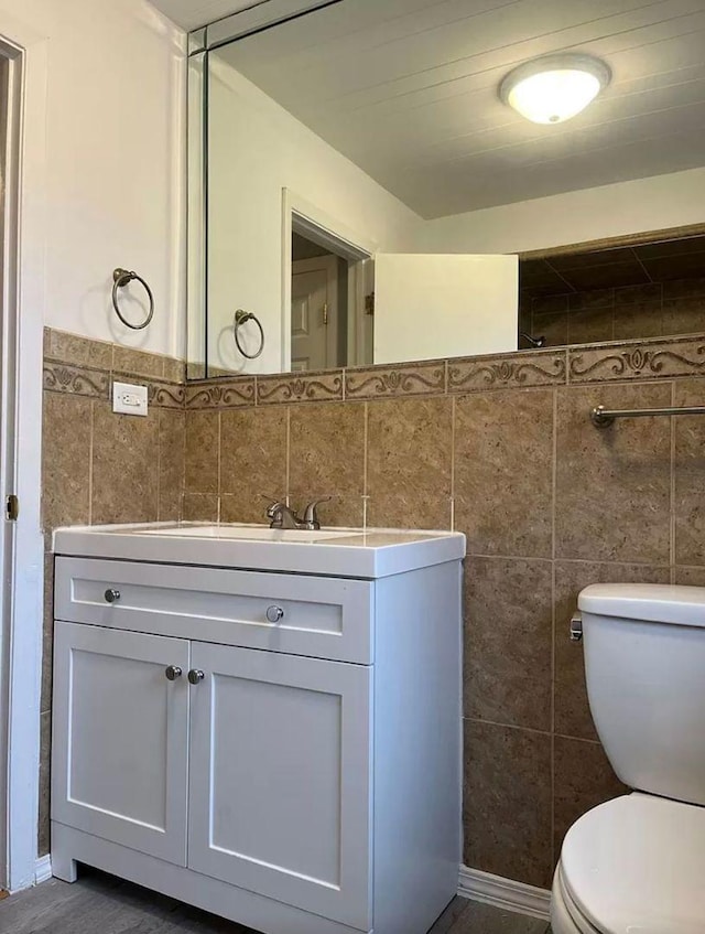 bathroom featuring tile walls, vanity, and toilet