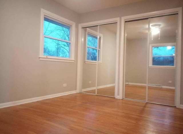 unfurnished bedroom with multiple closets and hardwood / wood-style flooring