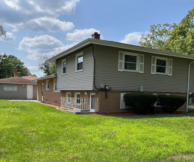 rear view of property featuring central AC and a lawn