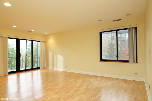 empty room featuring light wood-style floors, baseboards, visible vents, and recessed lighting