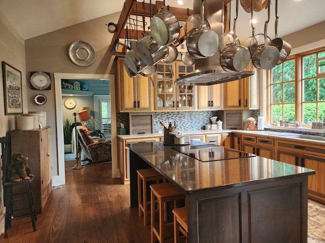 kitchen with tasteful backsplash, a center island, black electric cooktop, lofted ceiling, and dark wood-type flooring