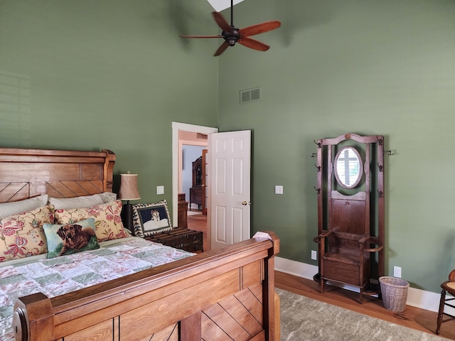 bedroom with dark wood-type flooring, ceiling fan, and a high ceiling