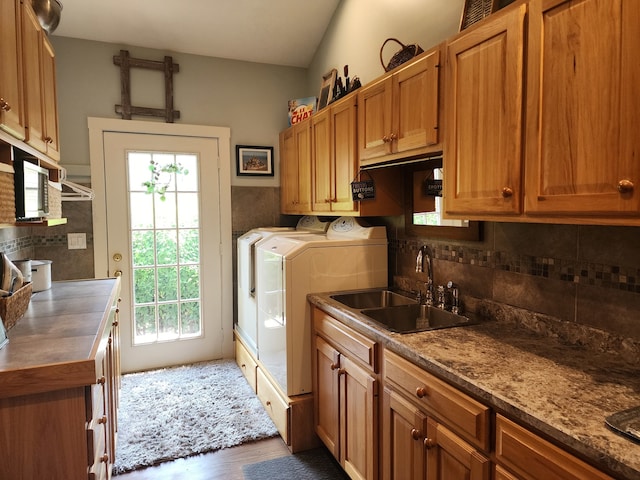 washroom featuring dark wood-type flooring, washing machine and dryer, a healthy amount of sunlight, and cabinets