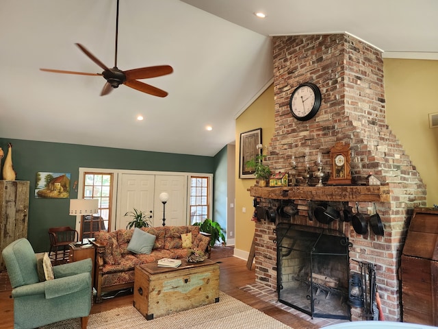 living room with lofted ceiling, ceiling fan, wood-type flooring, and a brick fireplace