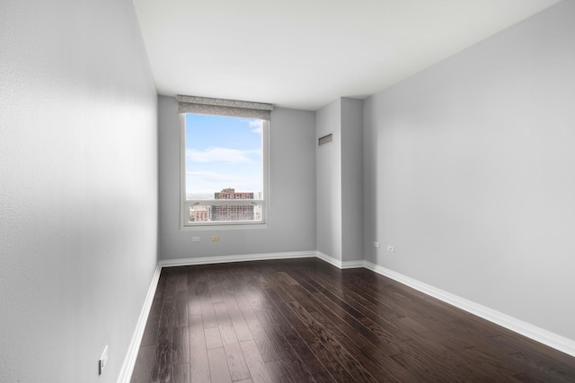 unfurnished room with baseboards and dark wood-style flooring