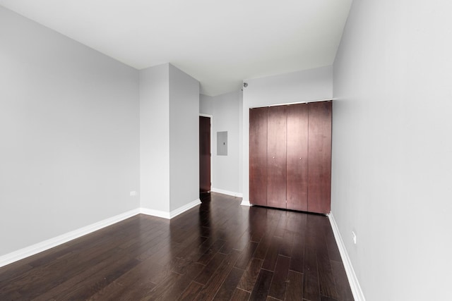 unfurnished bedroom featuring dark wood-style flooring, electric panel, and baseboards