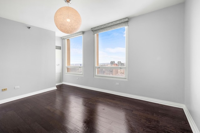 spare room featuring baseboards and dark wood finished floors