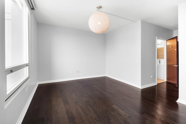 empty room with dark wood-type flooring and baseboards