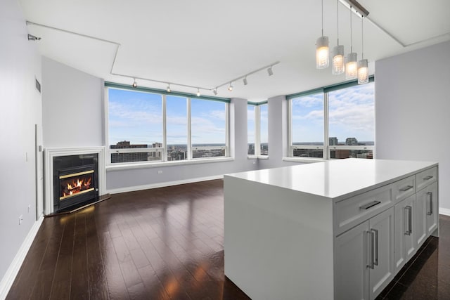 kitchen with a glass covered fireplace, plenty of natural light, dark wood finished floors, and decorative light fixtures