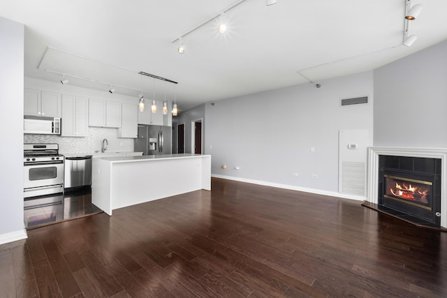 kitchen with visible vents, decorative backsplash, a tiled fireplace, appliances with stainless steel finishes, and open floor plan