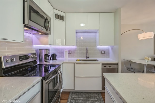 kitchen with white cabinetry, stainless steel appliances, decorative backsplash, sink, and dark hardwood / wood-style floors