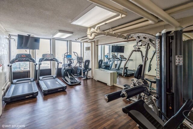 gym with a wall of windows, wood-type flooring, and a textured ceiling