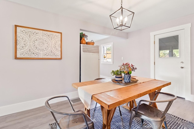 dining space featuring wood-type flooring and a notable chandelier