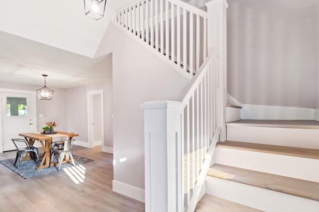 staircase featuring hardwood / wood-style flooring and a notable chandelier