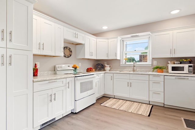 kitchen with sink, white cabinets, white appliances, and light hardwood / wood-style floors