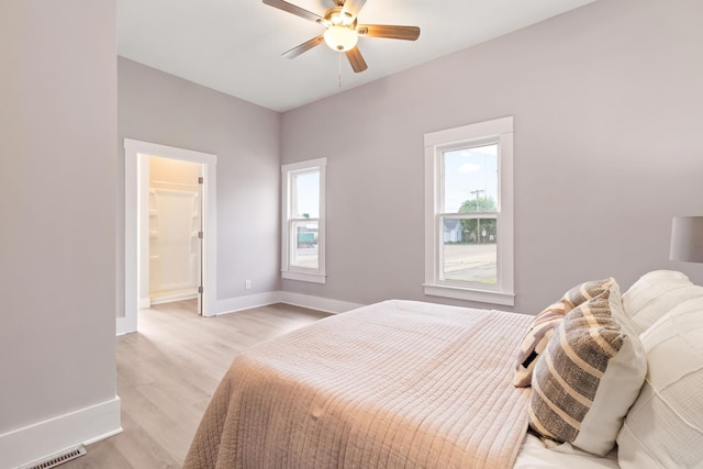 bedroom featuring a spacious closet, light hardwood / wood-style floors, and ceiling fan