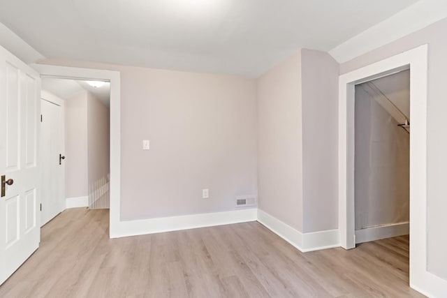 spare room featuring vaulted ceiling and light wood-type flooring