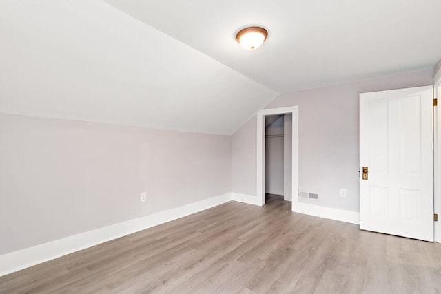 additional living space featuring lofted ceiling and light hardwood / wood-style flooring