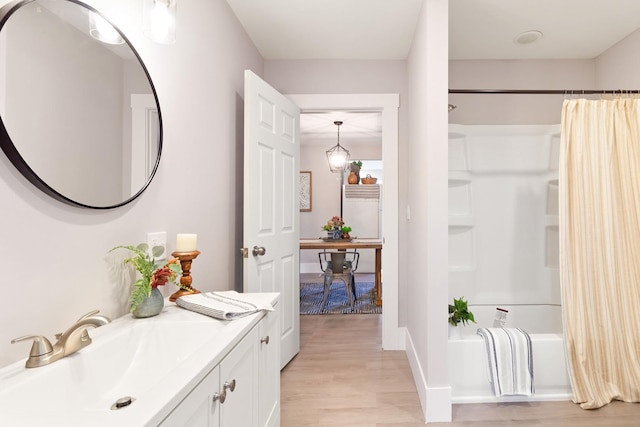 bathroom featuring wood-type flooring, shower / bath combination with curtain, and vanity