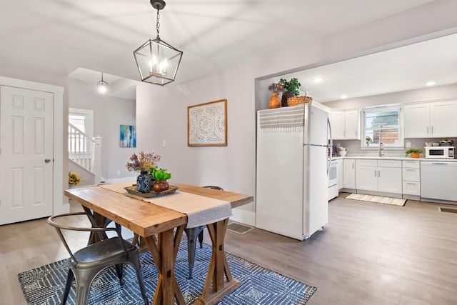 dining space featuring an inviting chandelier, sink, and wood-type flooring