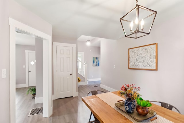 dining space with light hardwood / wood-style floors and a notable chandelier