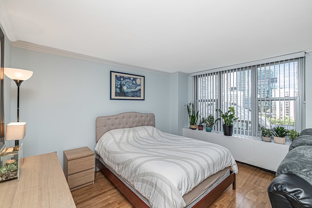 bedroom featuring wood-type flooring and ornamental molding