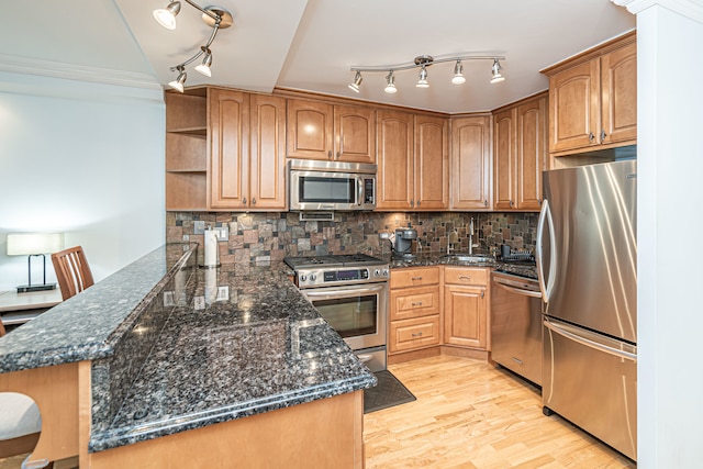 kitchen with backsplash, appliances with stainless steel finishes, light hardwood / wood-style flooring, and dark stone counters