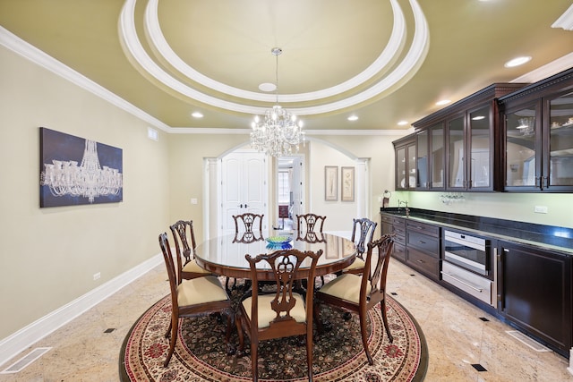 tiled dining space with ornamental molding, an inviting chandelier, and a tray ceiling