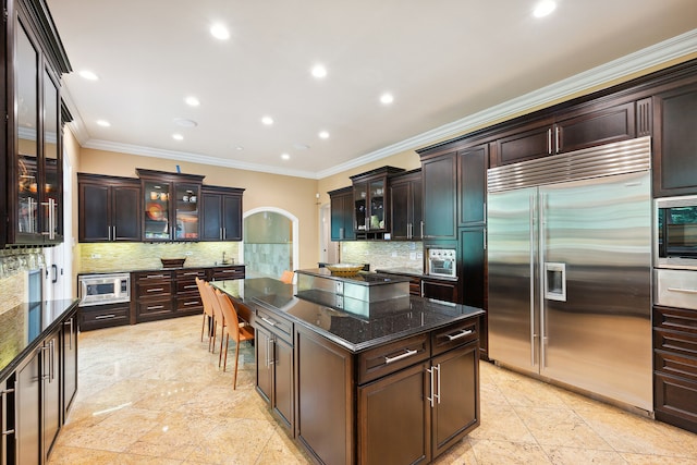 kitchen with dark brown cabinets, backsplash, and built in appliances