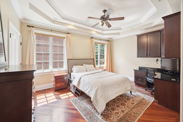 bedroom featuring light hardwood / wood-style floors, crown molding, ceiling fan, and a raised ceiling