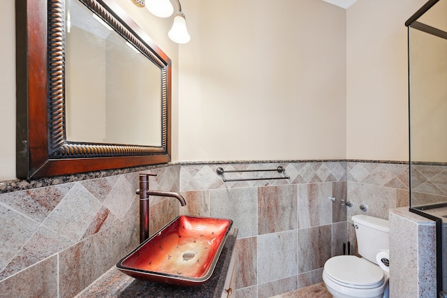 bathroom with tile walls, toilet, tasteful backsplash, and sink