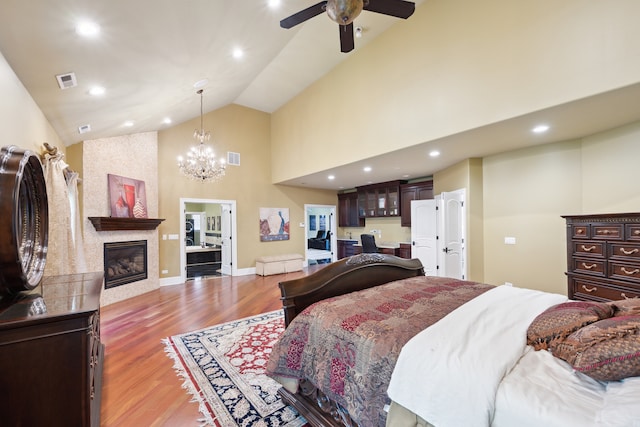 bedroom with hardwood / wood-style floors, high vaulted ceiling, a fireplace, and ceiling fan with notable chandelier