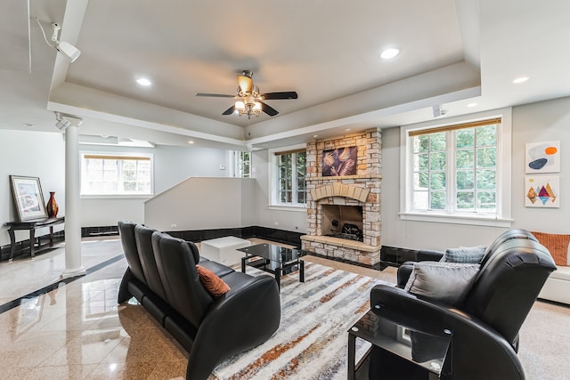 living room with a fireplace, a tray ceiling, and ceiling fan