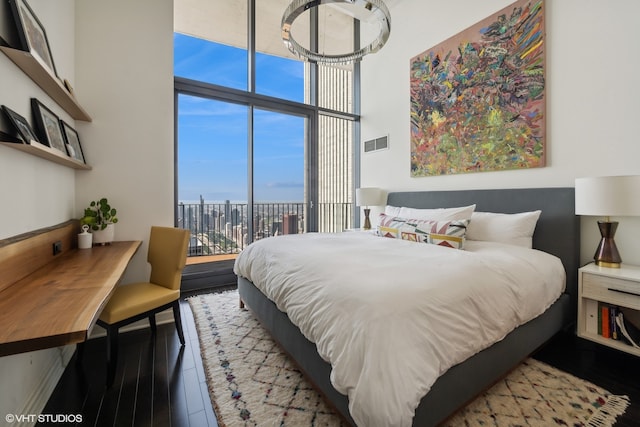 bedroom featuring a towering ceiling, expansive windows, and a water view