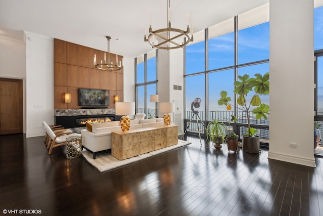 living room with a wall of windows, a fireplace, a chandelier, and a towering ceiling