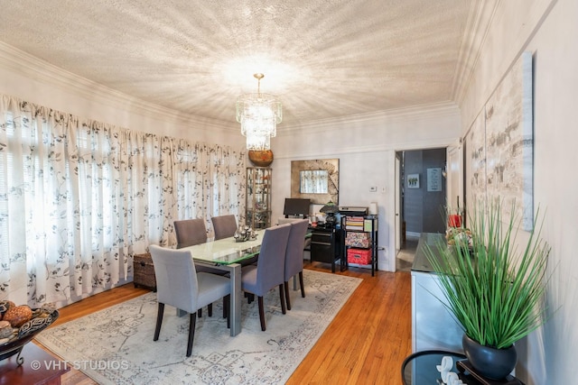 dining area with crown molding, hardwood / wood-style flooring, a textured ceiling, and a notable chandelier