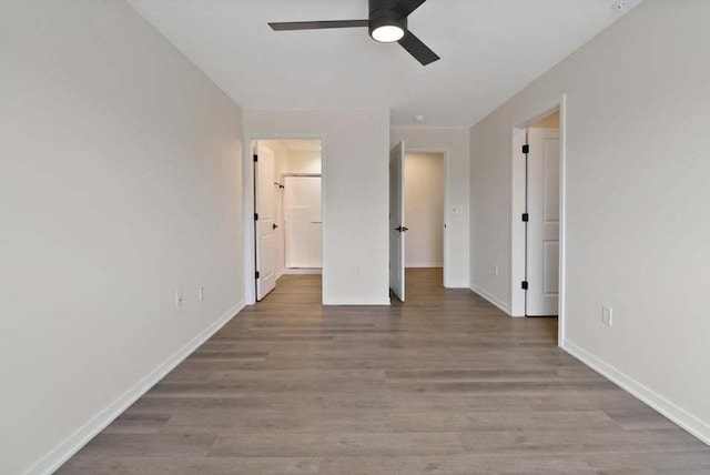 unfurnished bedroom with ceiling fan, ensuite bath, light wood-style flooring, and baseboards