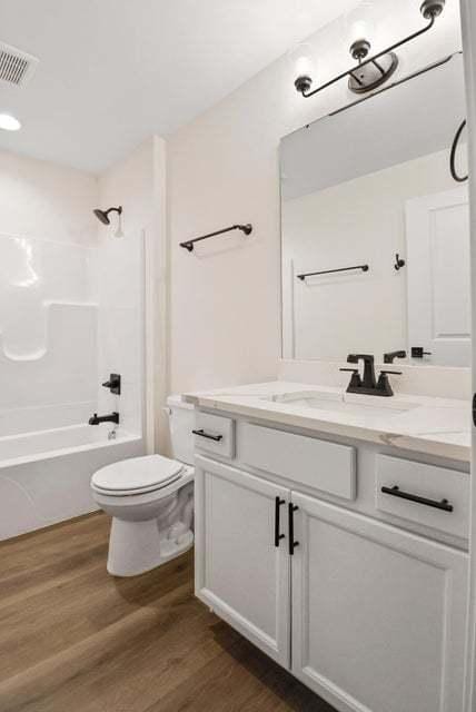 full bathroom featuring visible vents, toilet, washtub / shower combination, vanity, and wood finished floors