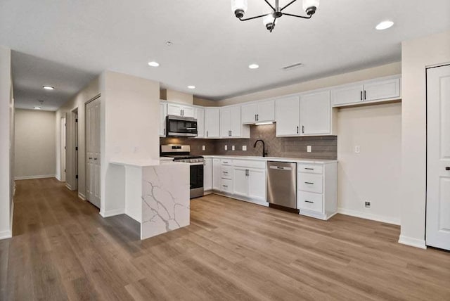 kitchen with appliances with stainless steel finishes, light wood-style flooring, and white cabinetry