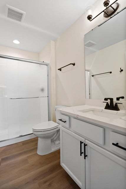 full bath with a shower stall, visible vents, wood finished floors, and vanity