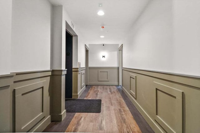 hallway featuring a wainscoted wall, dark wood-type flooring, and recessed lighting