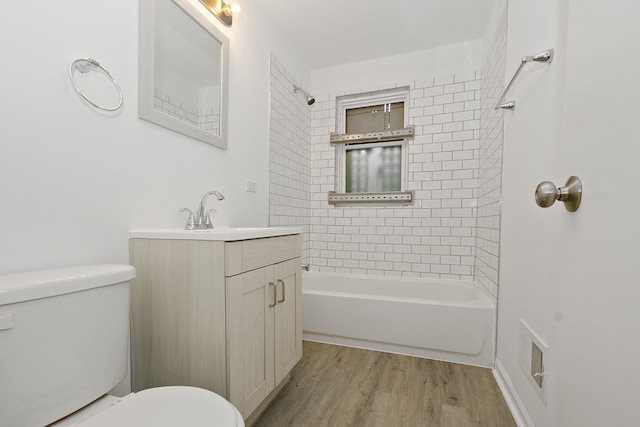 full bathroom with hardwood / wood-style flooring, tiled shower / bath combo, toilet, and vanity