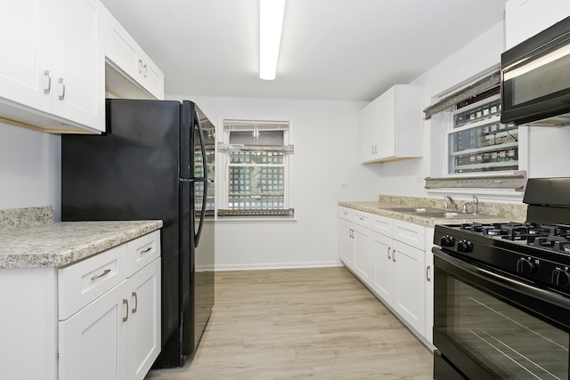 kitchen featuring sink, black appliances, white cabinets, and light wood-type flooring