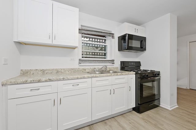 kitchen with white cabinetry, light stone counters, light hardwood / wood-style floors, black appliances, and sink