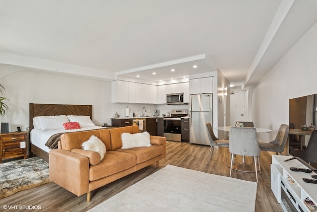 bedroom featuring wood-type flooring, stainless steel refrigerator, and sink